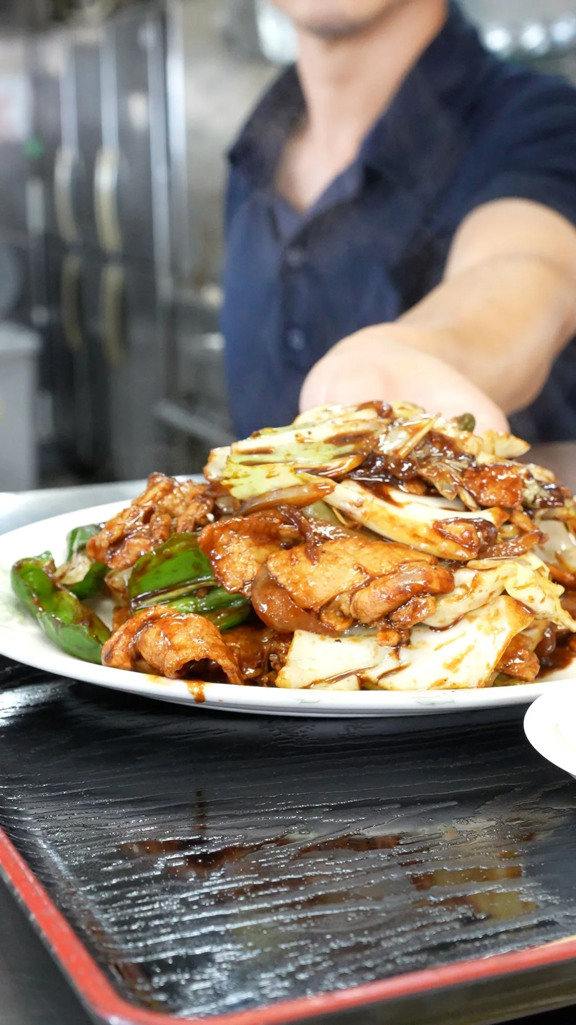 店主が差し出す回鍋肉。週替わり定食の一皿